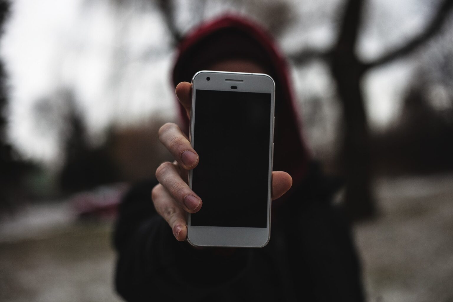 Girl with a phone in her hand. The hand is stretched forward and the phone is pointed to the user, it also covers her face.