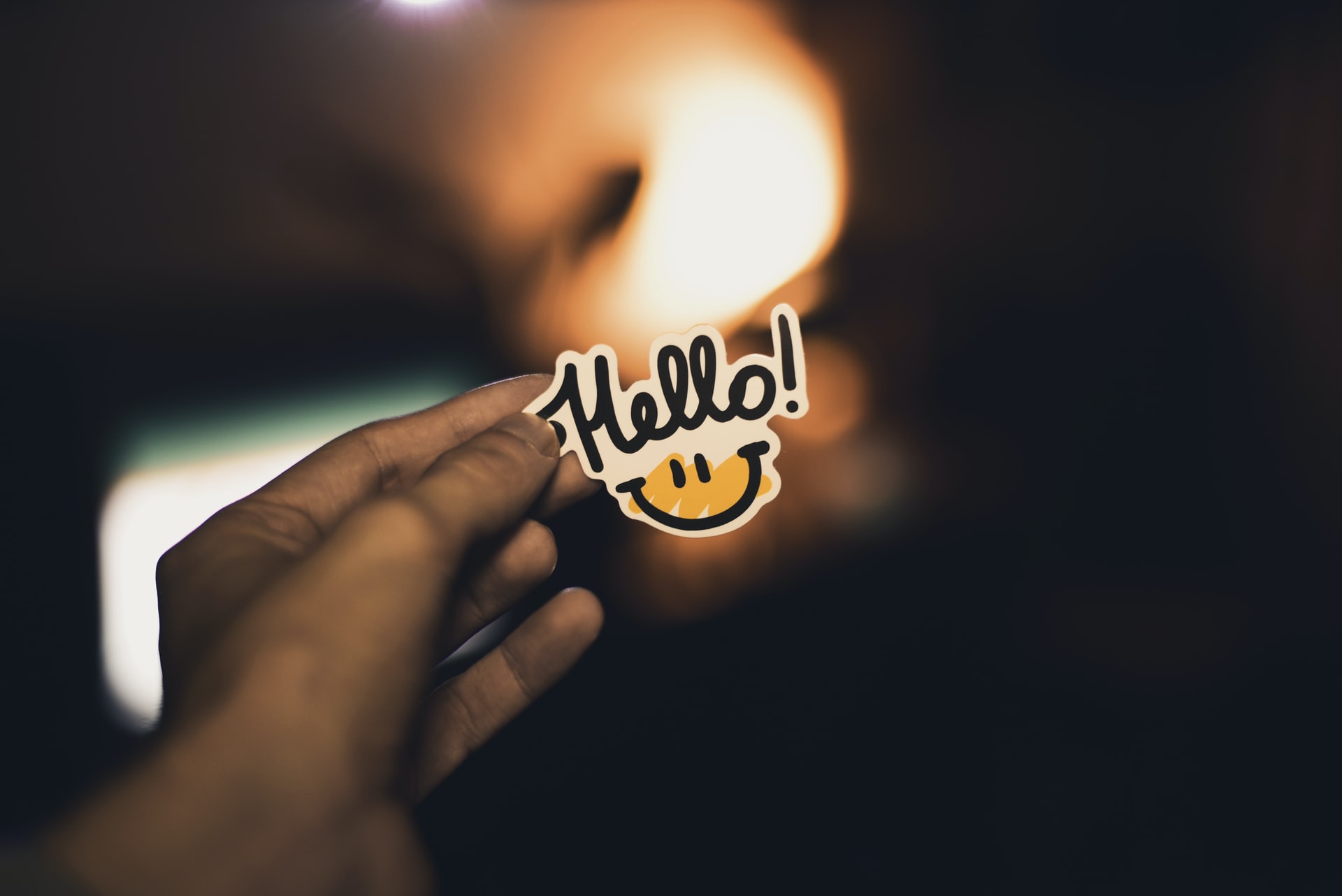 A person holding a "hello" sticker.