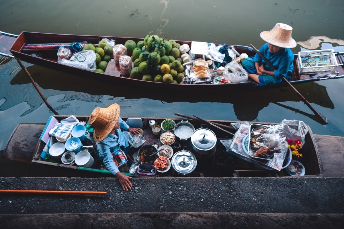 "Female traders in boats laden with local food and fruits at the floating market of Thailand"