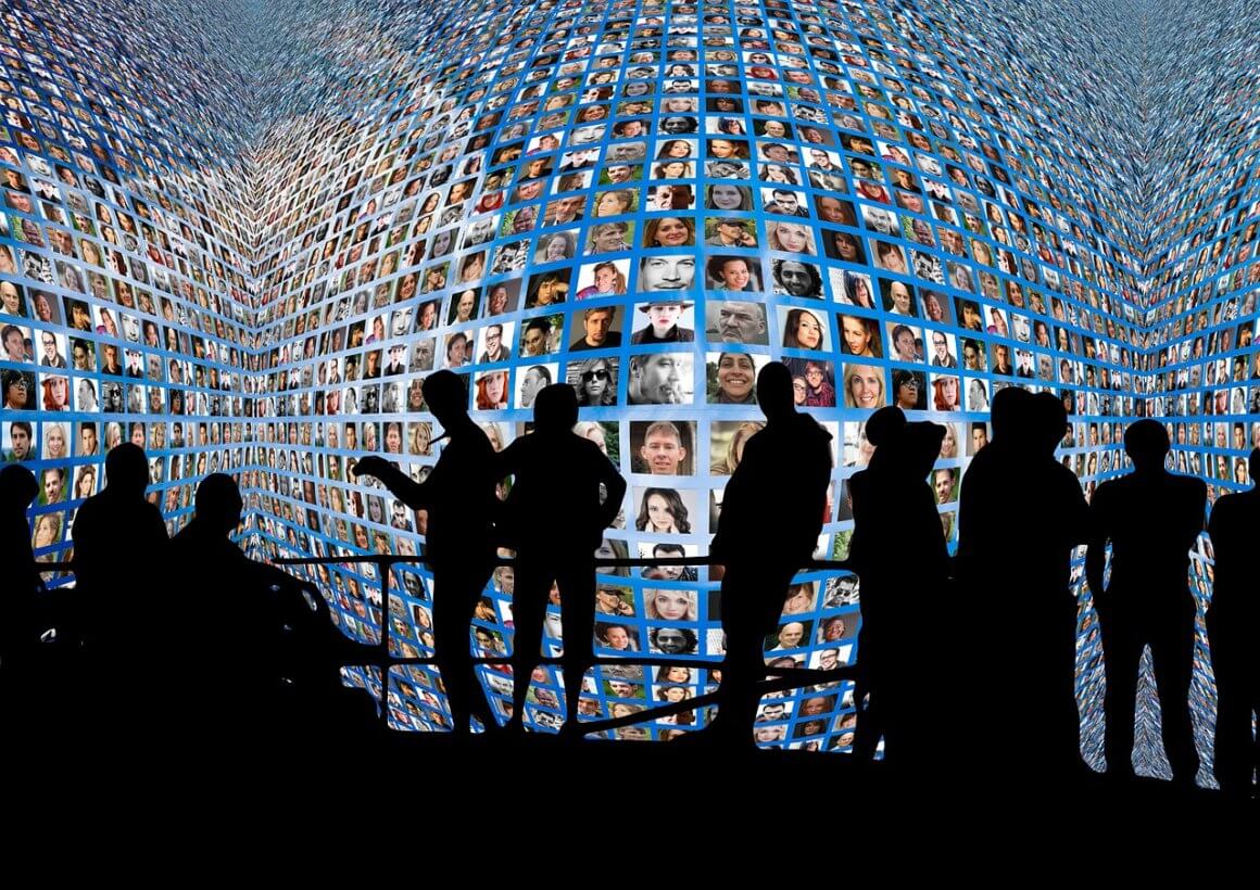 Silhouette photograph of a group of people standing in front of a screen with a collage of multiple people