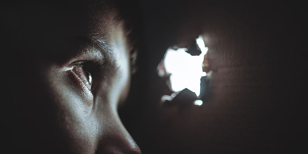 a child peeping through a hole in the wall