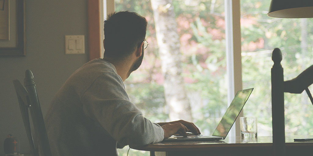 A remote employee sitting on his desk with the laptop open and out the door