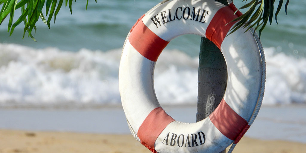 image of a lifebuoy attached to a tree by the beach with the words, welcome aboard written on it 