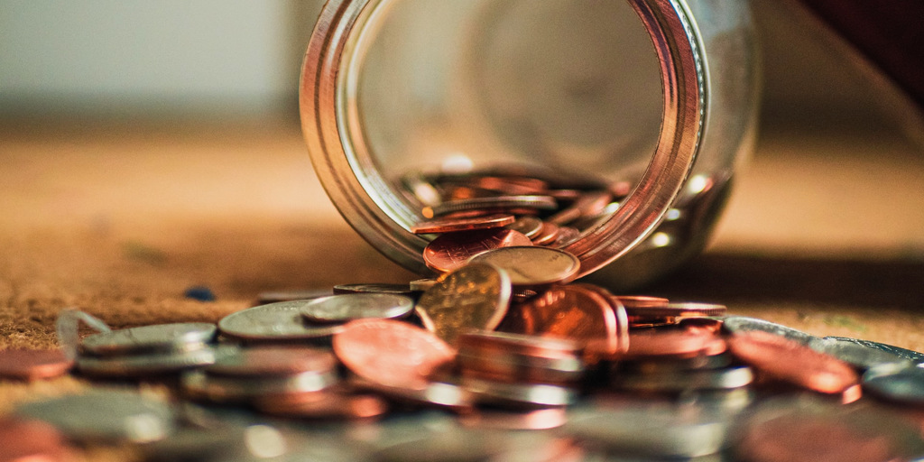 Coins falling out of a glass jar.