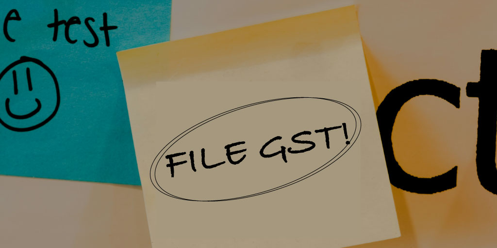 close up photo of a post-it note saying "file GST!" on a noticeboard