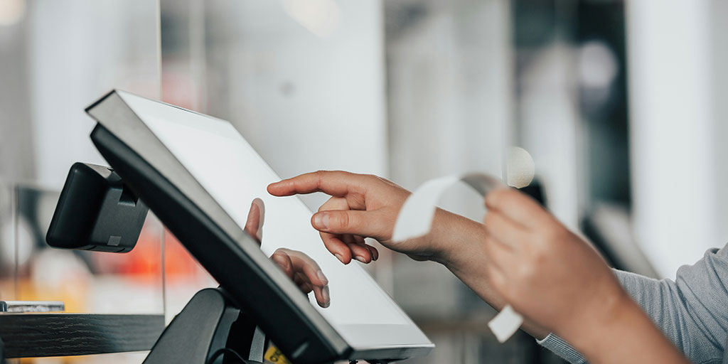 close up photo of person verifying a physical receipt against a POS system