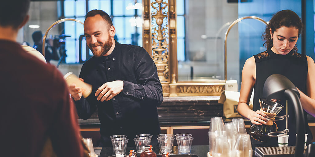 Photo of a couple of bar staff serving customers